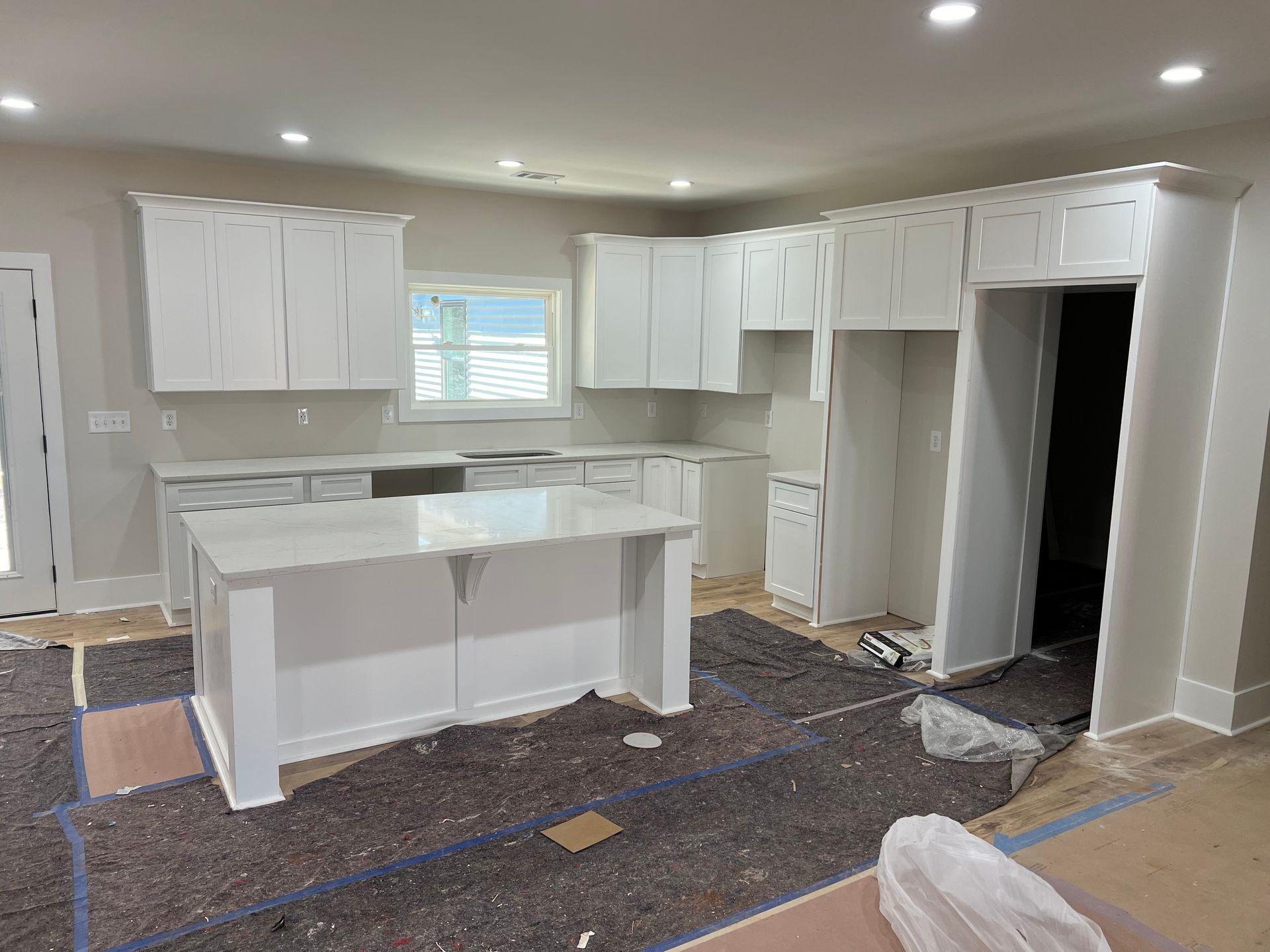 Kitchen under construction with white cabinets, island, and light gray walls.