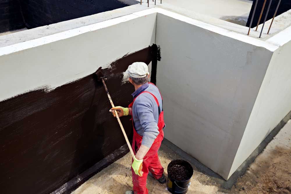 Worker Waterproofing A Building Foundation