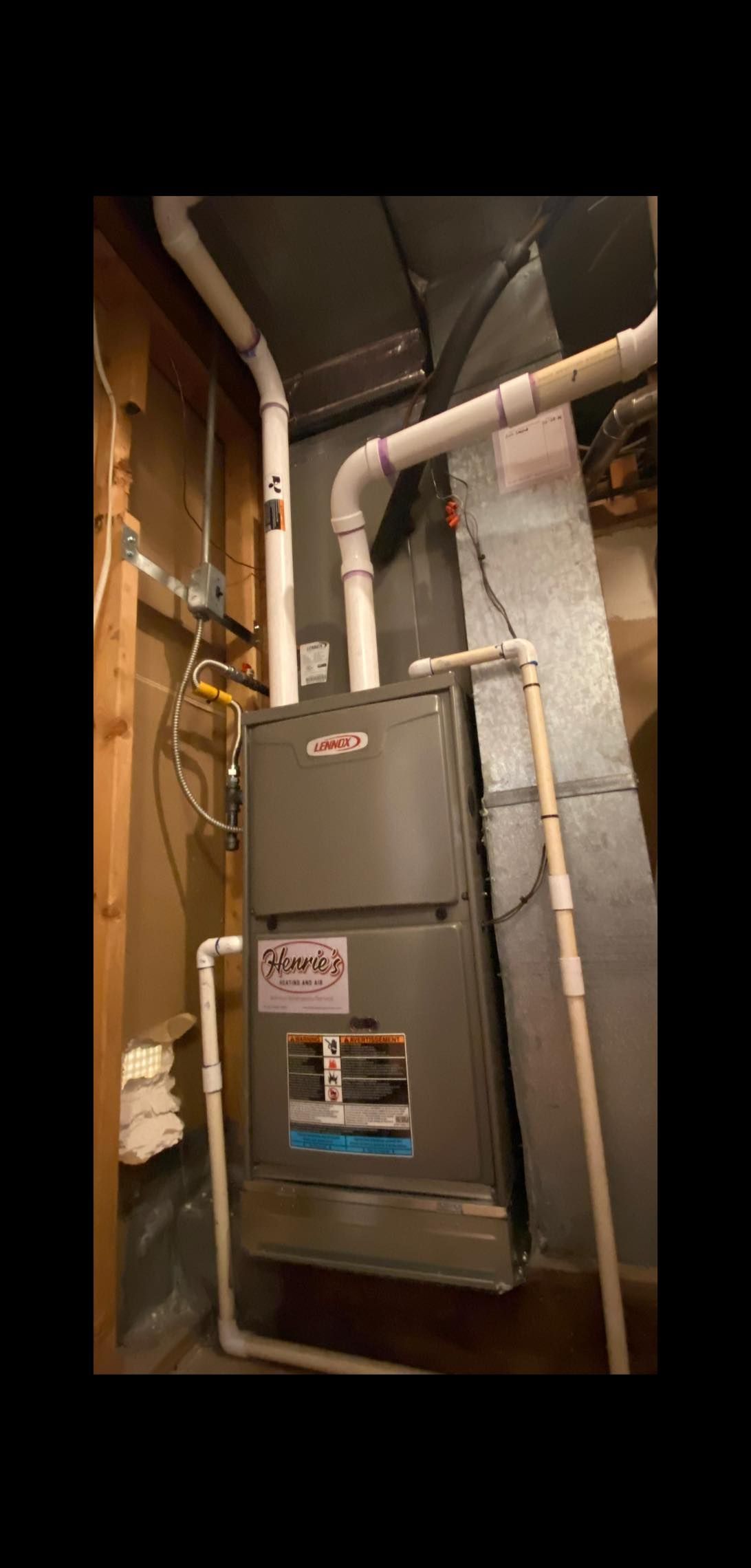Furnace with white pipes in a basement setting.