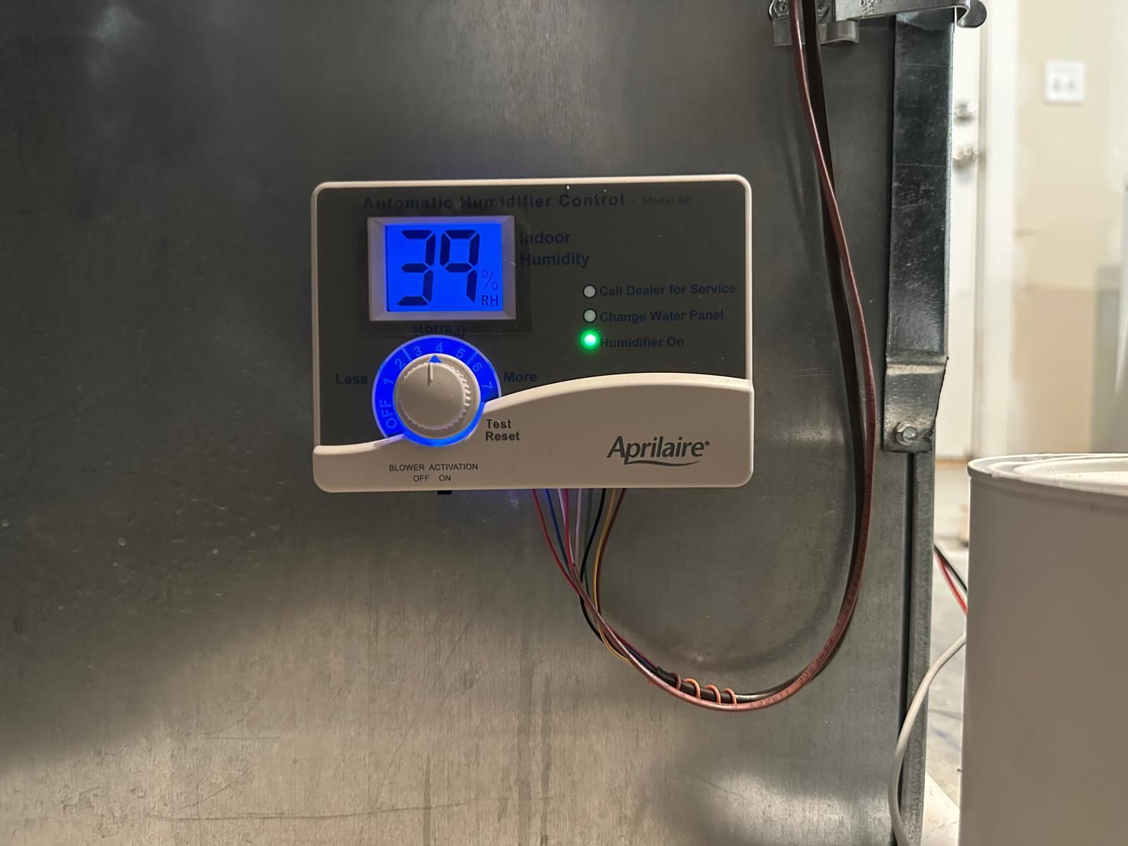 A gray humidifier control panel with a blue digital display showing