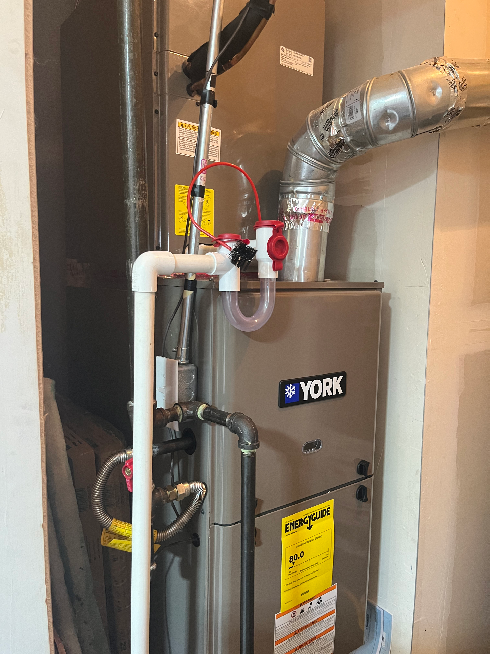 A York furnace in a room, with white PVC piping, a condensation pump, and ductwork.