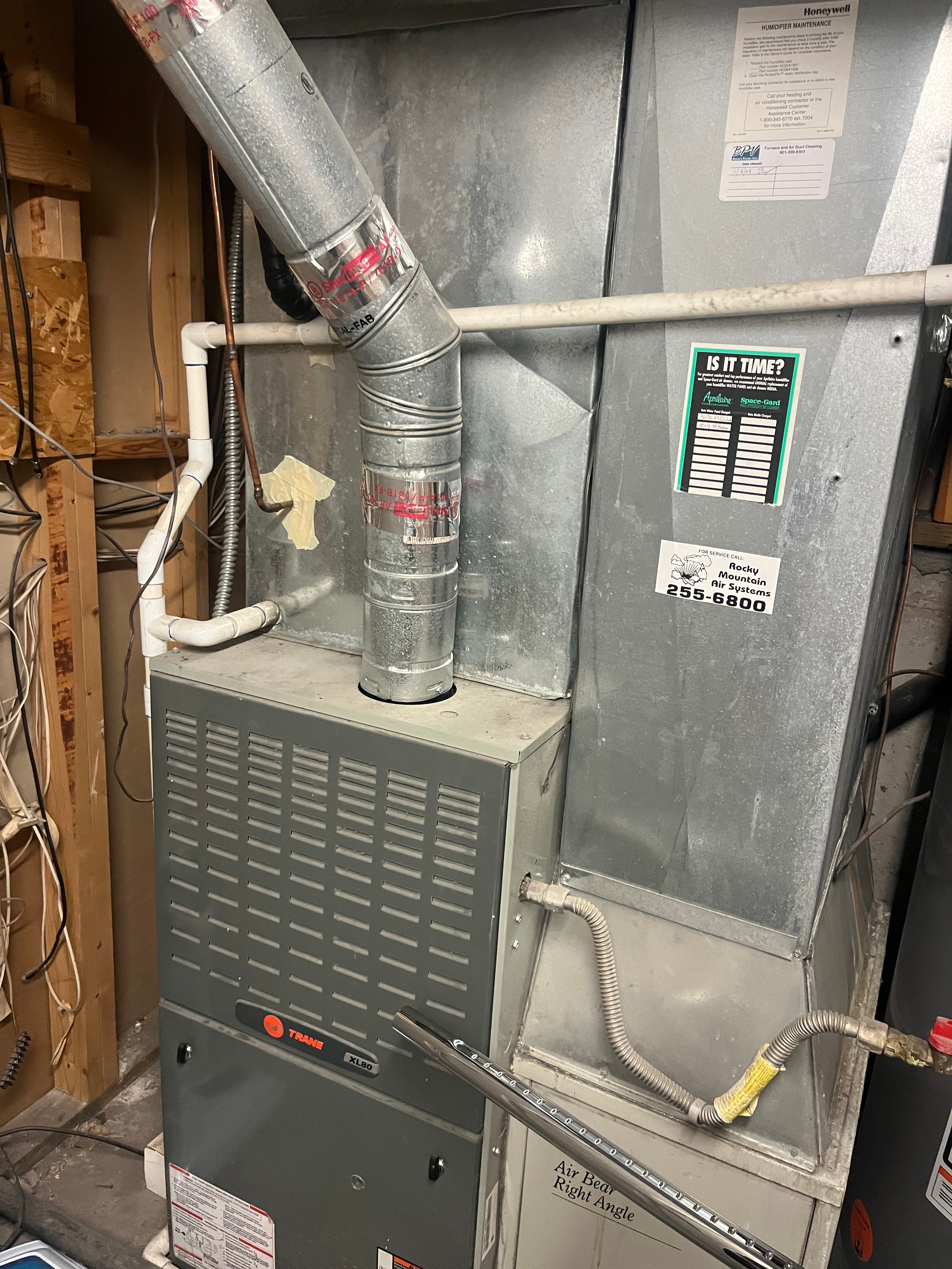 A Trane furnace with ductwork in a utility room. Gray metal and silver ducting.