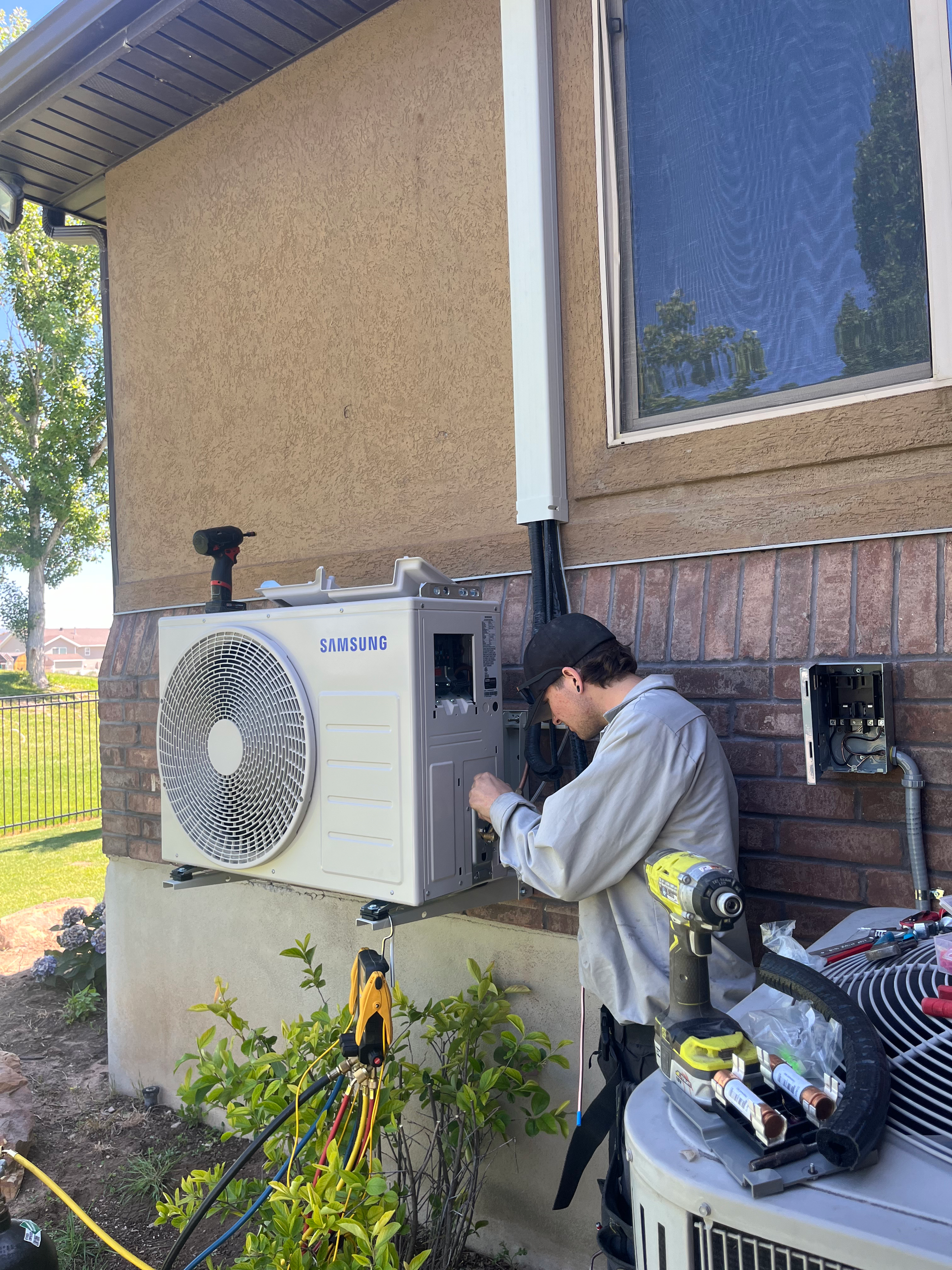 Man installing an AC unit on the exterior wall of a building.