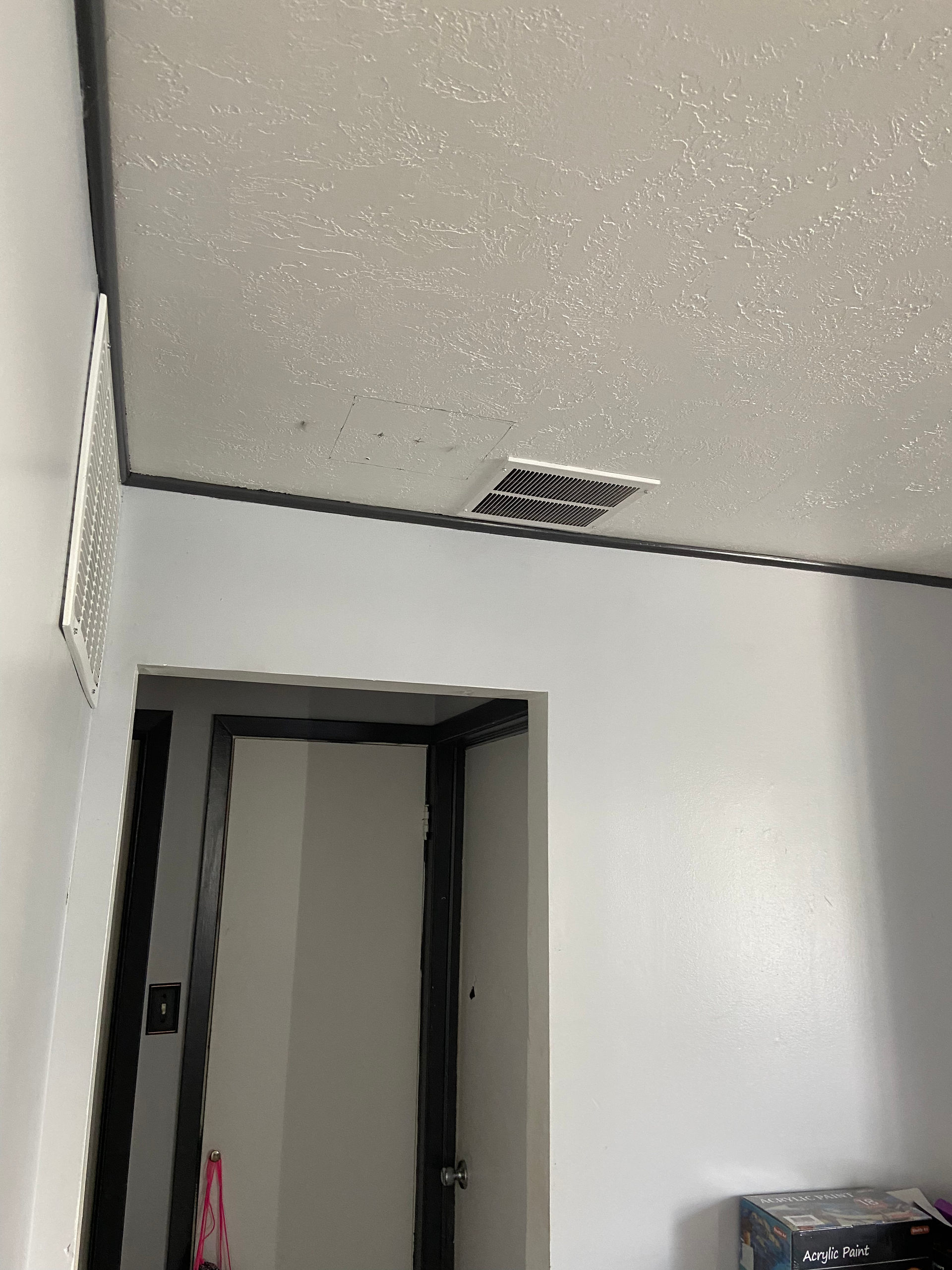 Ceiling with a vent, an air conditioning unit, and a doorway. Walls are painted gray.