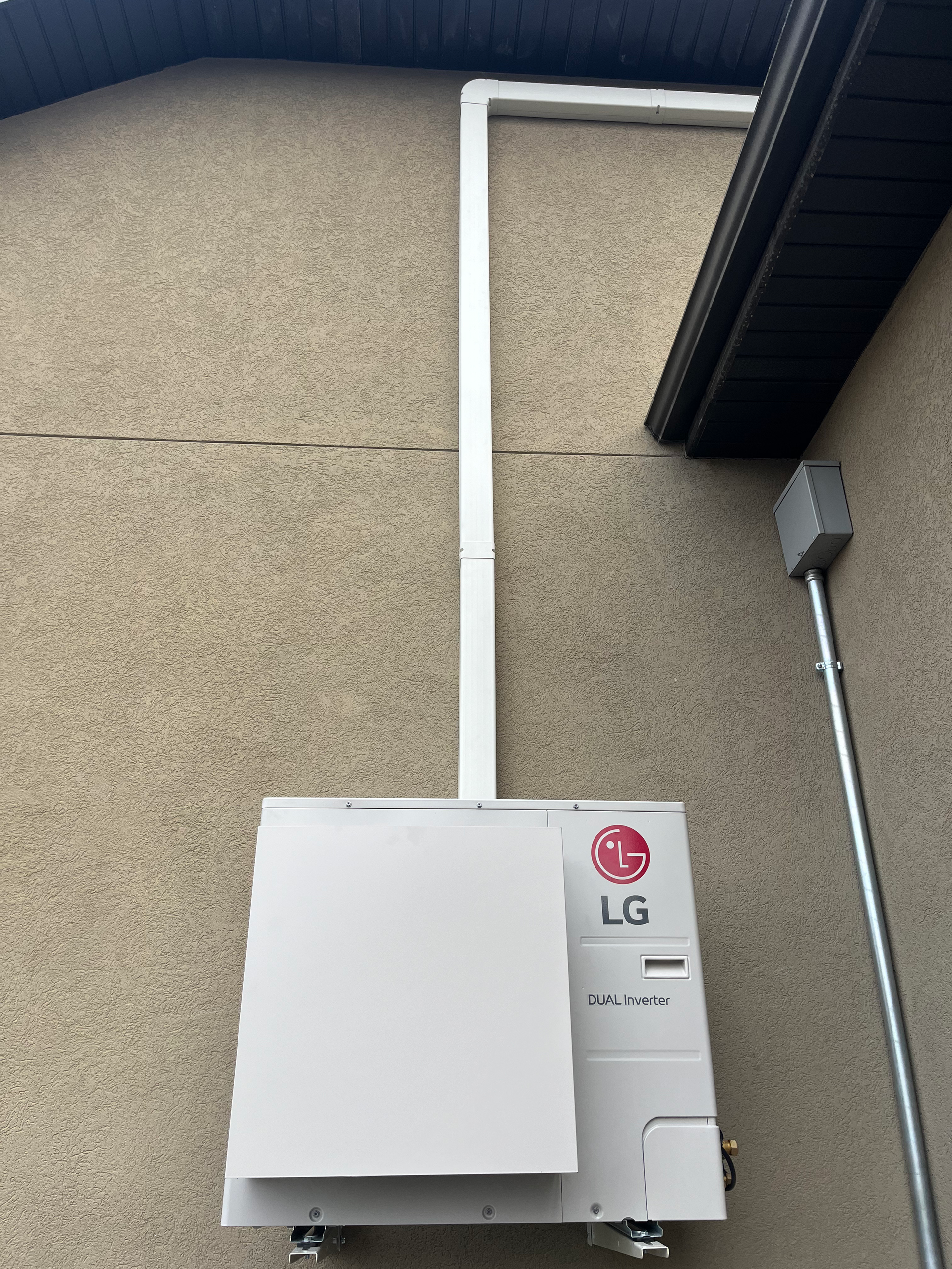 LG solar battery unit mounted on a stucco wall with white conduit running to the roof.