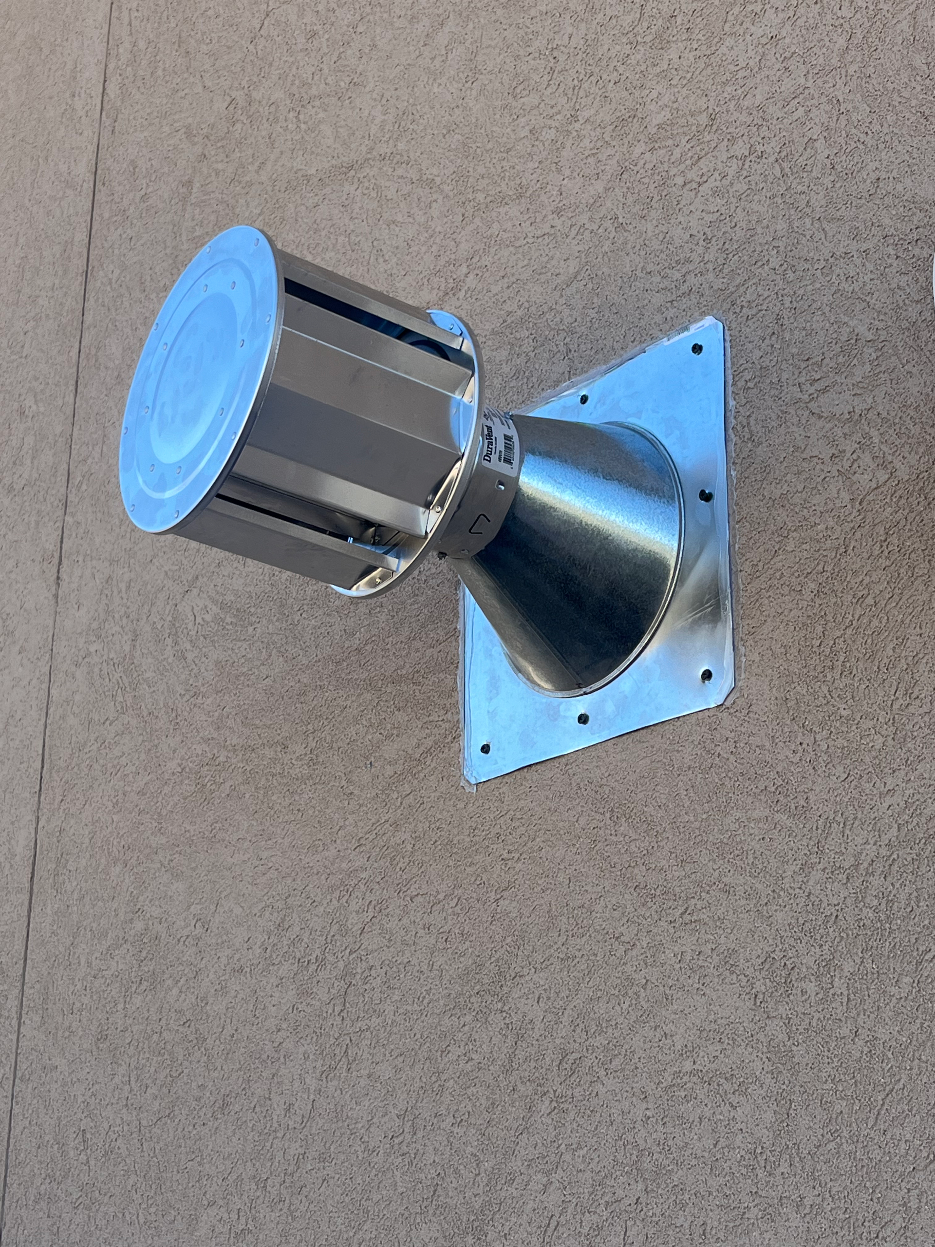 Silver spotlight attached to a wall with a square metal plate.