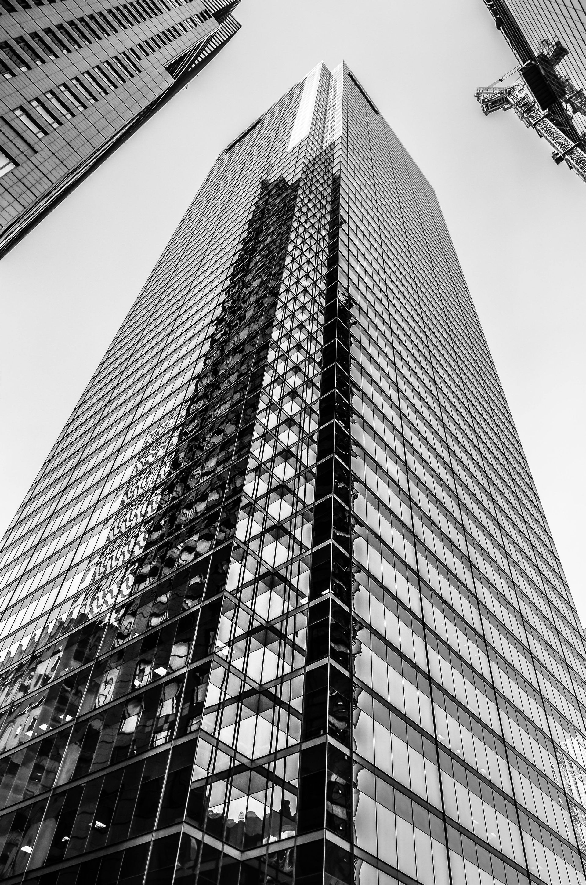 Black and white image of a tall skyscraper, looking upwards from the base.