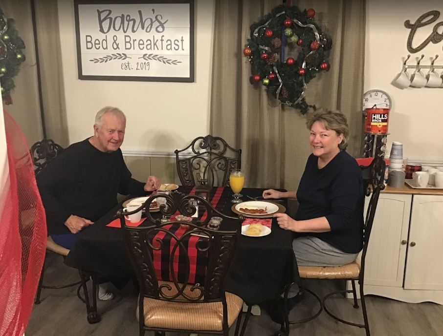 A man and a woman are sitting at a table with plates of food.