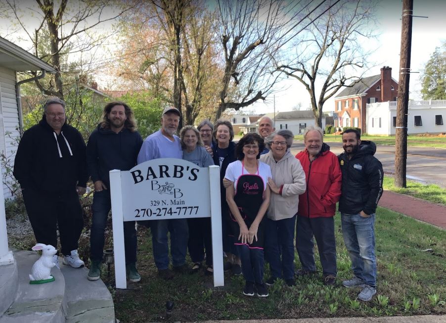 A group of people standing in front of a sign that says barb 's