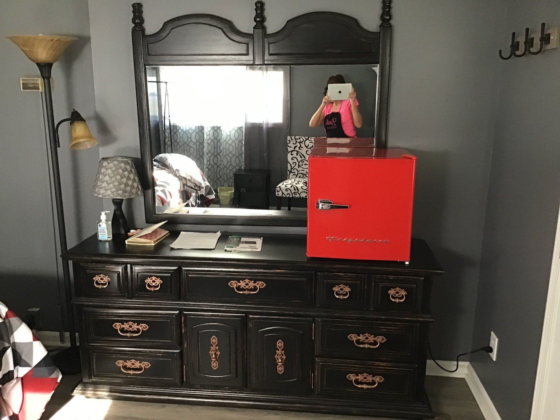 A bedroom with a black dresser and a red refrigerator