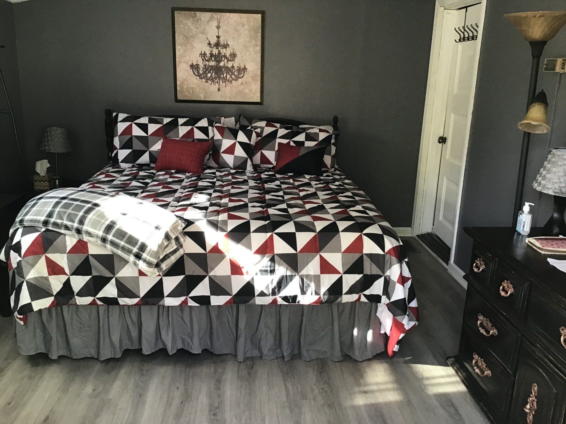 A bedroom with a bed , dresser , lamp and a picture on the wall.