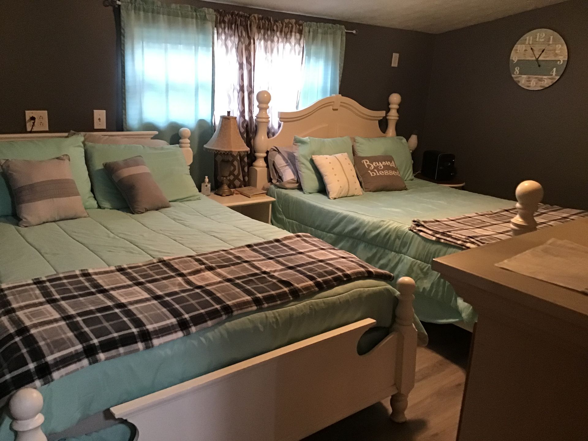 A bedroom with two beds and a clock on the wall.
