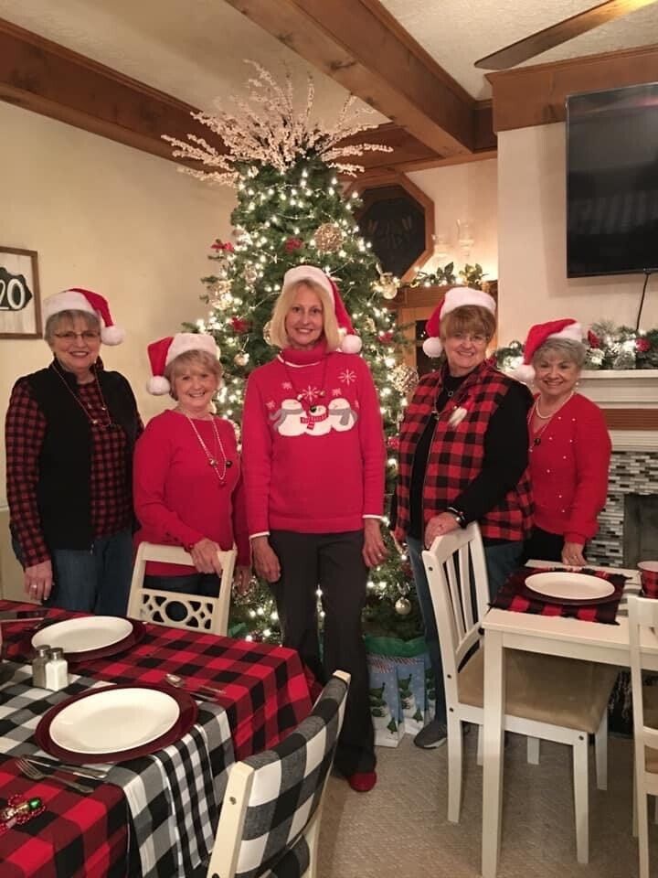 A group of women are standing in front of a christmas tree.
