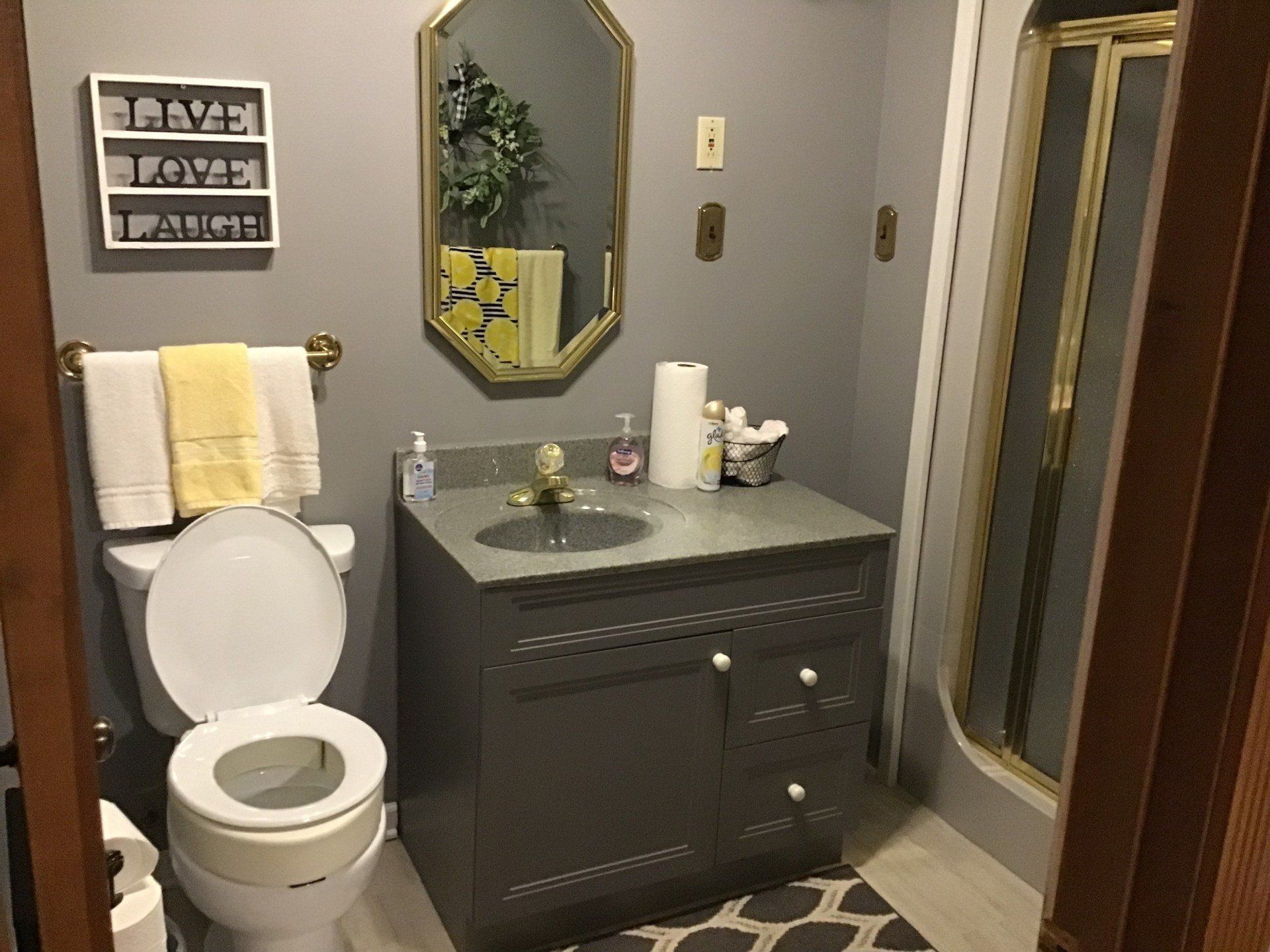 A bathroom with a toilet , sink , mirror and shower.