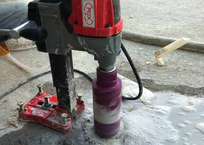 A construction worker is kneeling down on a brick walkway.