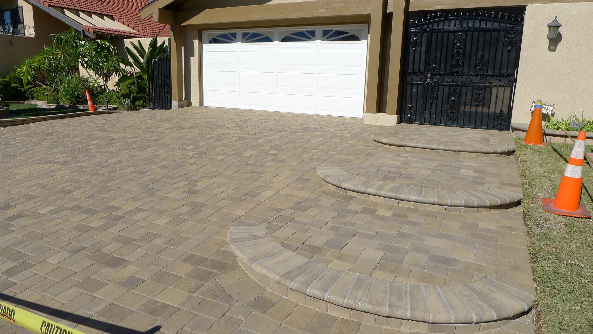 A construction worker is kneeling down on a brick walkway.