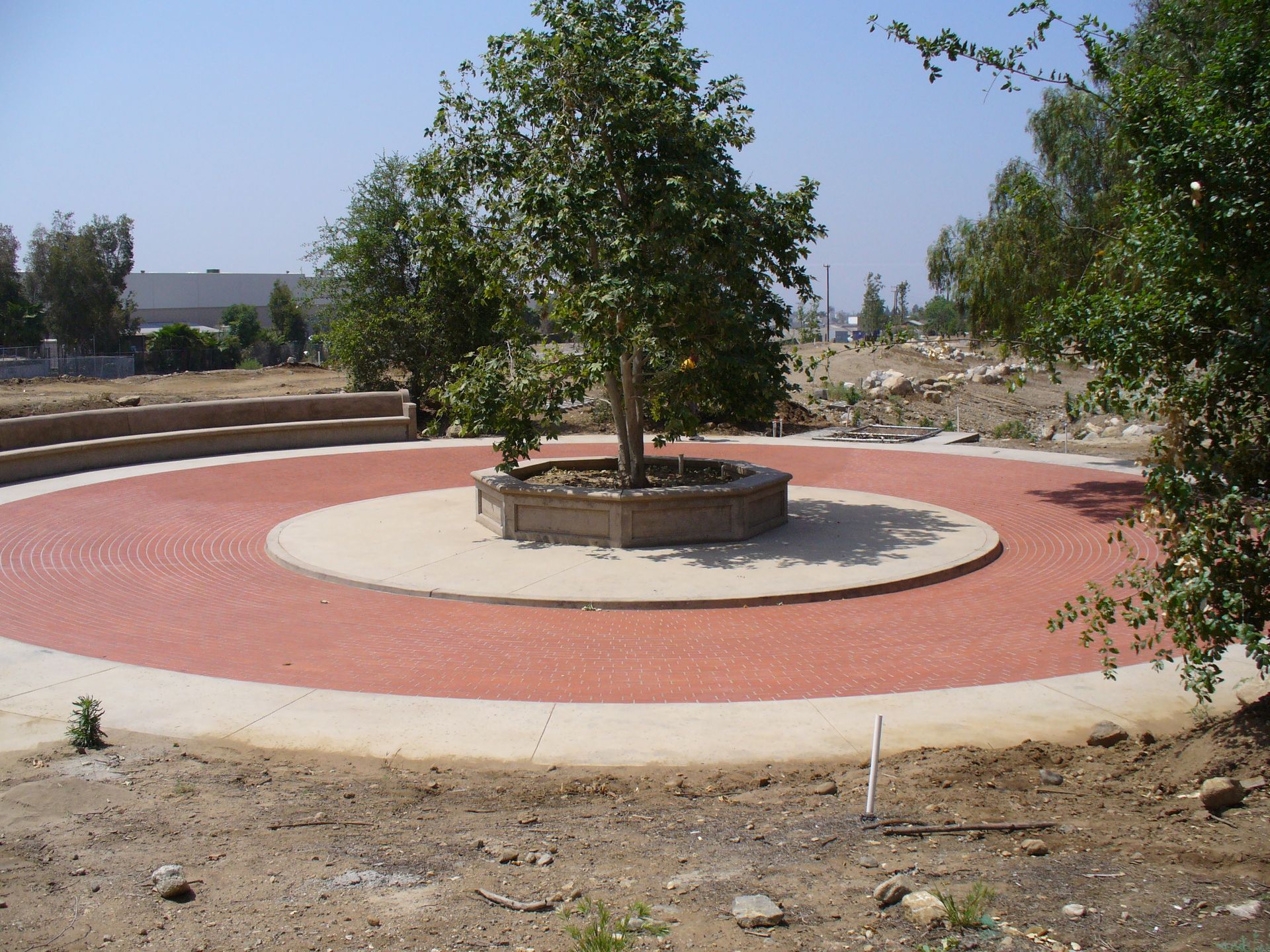 A construction worker is kneeling down on a brick walkway.