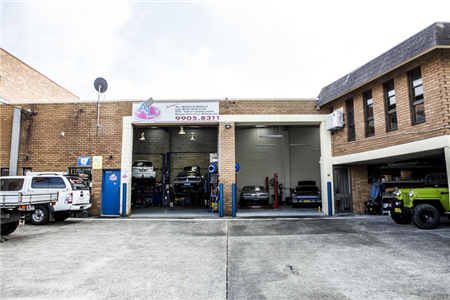 A jeep is parked in front of a car repair shop.