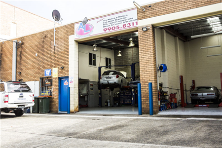A car is sitting on a lift in a garage.