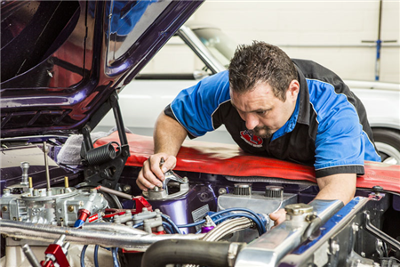 A man is working on the engine of a car.