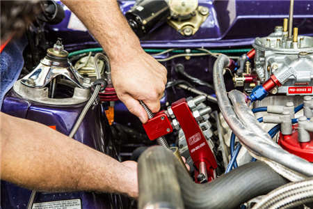 A man is working on a purple car engine with a wrench.