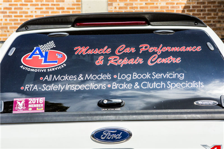 A white ford truck with a sticker on the back window that says muscle car performance & repair centre