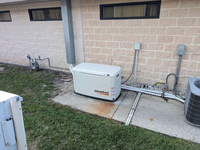 Man starting a red generator next to a white RV, person looks out the door, sunny outdoor setting.
