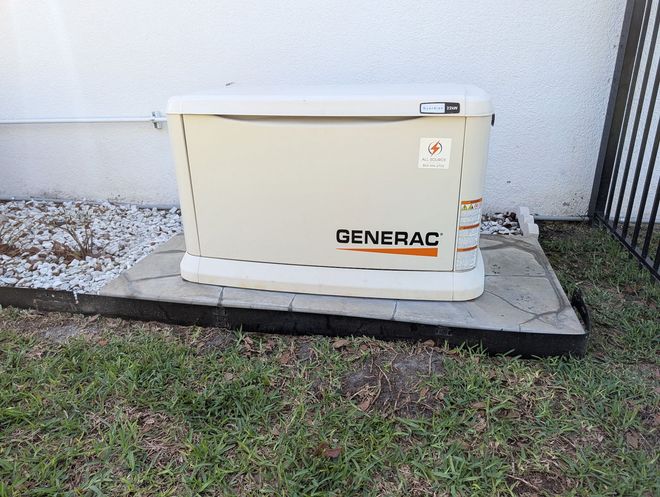 Man starting a red generator next to a white RV, person looks out the door, sunny outdoor setting. Man starting a red generator next to a white RV, person looks out the door, sunny outdoor setting.