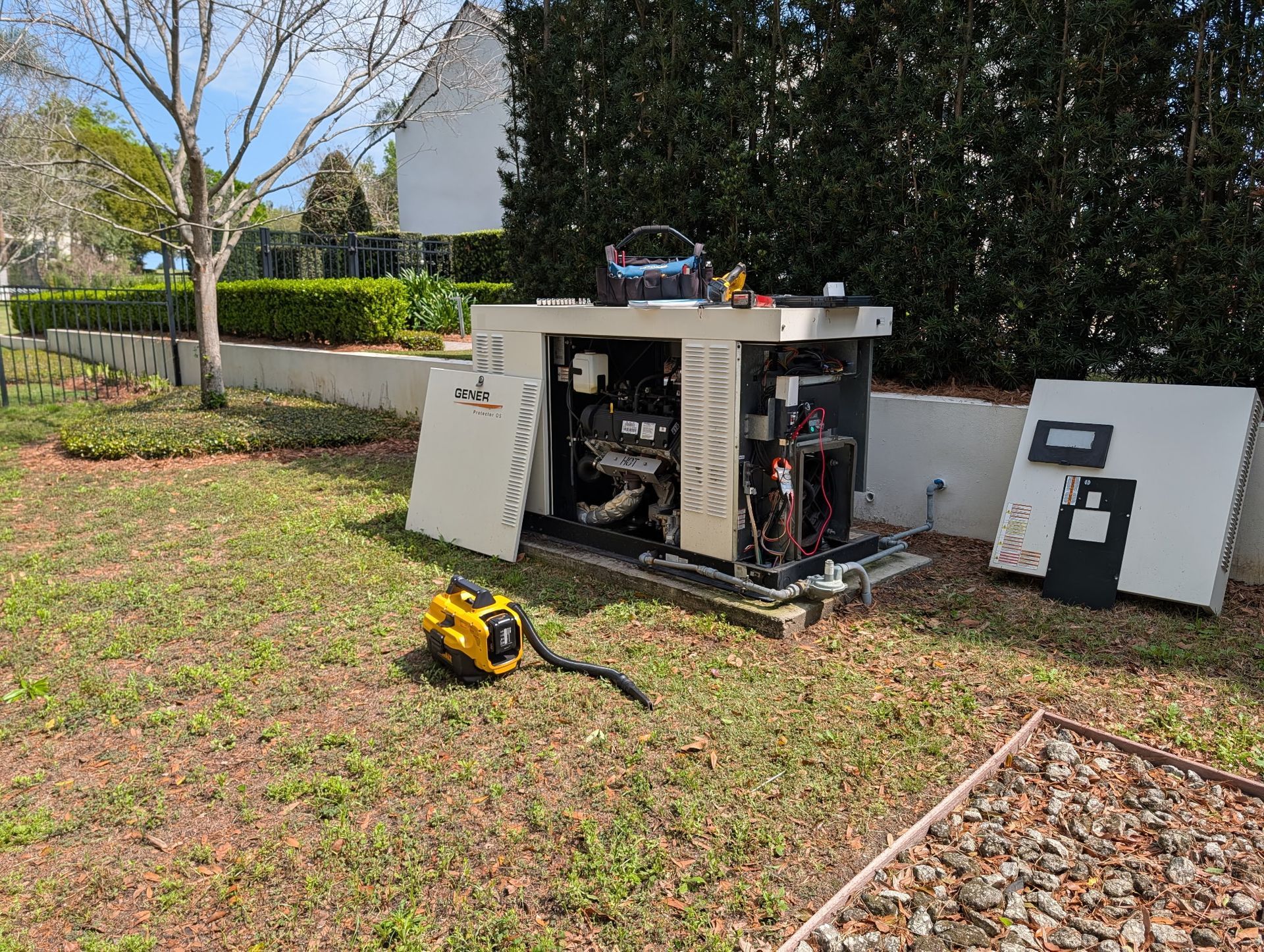 Dark green Briggs & Stratton generator on a concrete pad next to a house, with green grass and foliage.