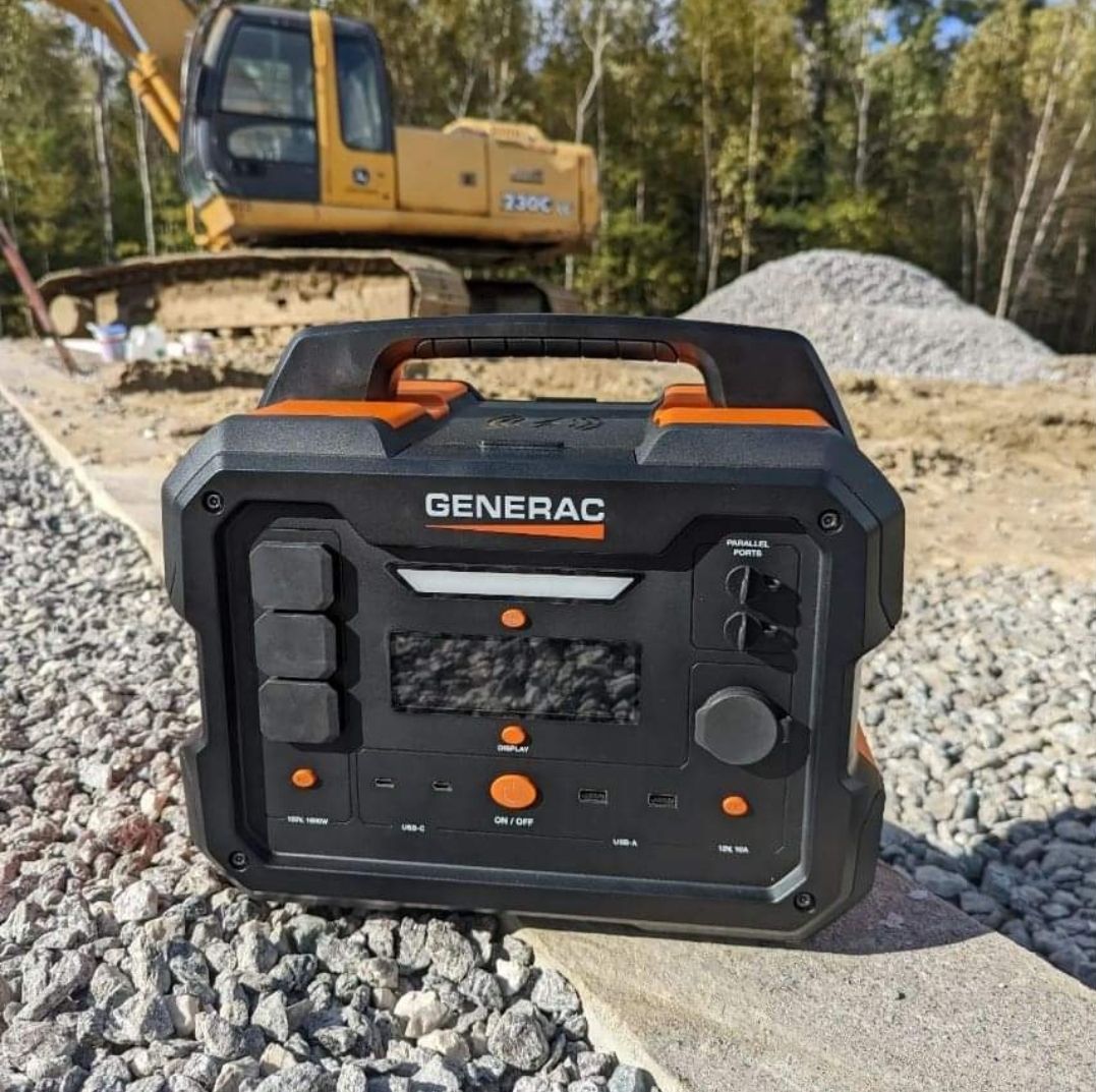 Person in blue sweatsuit pulls a blue generator with a handle across a concrete floor.