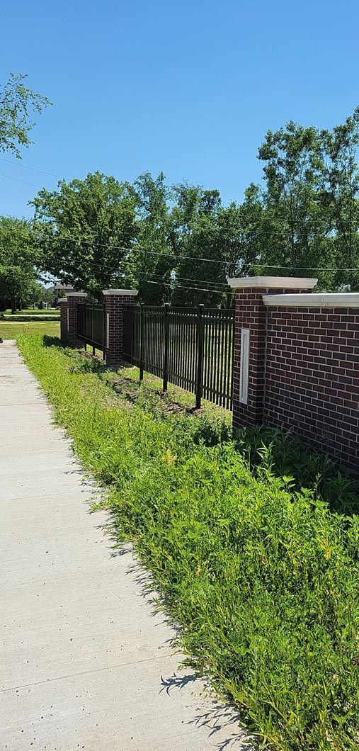 A brick post and metal fence in Troy, MI in a backyard in by Elite Wood Fencing