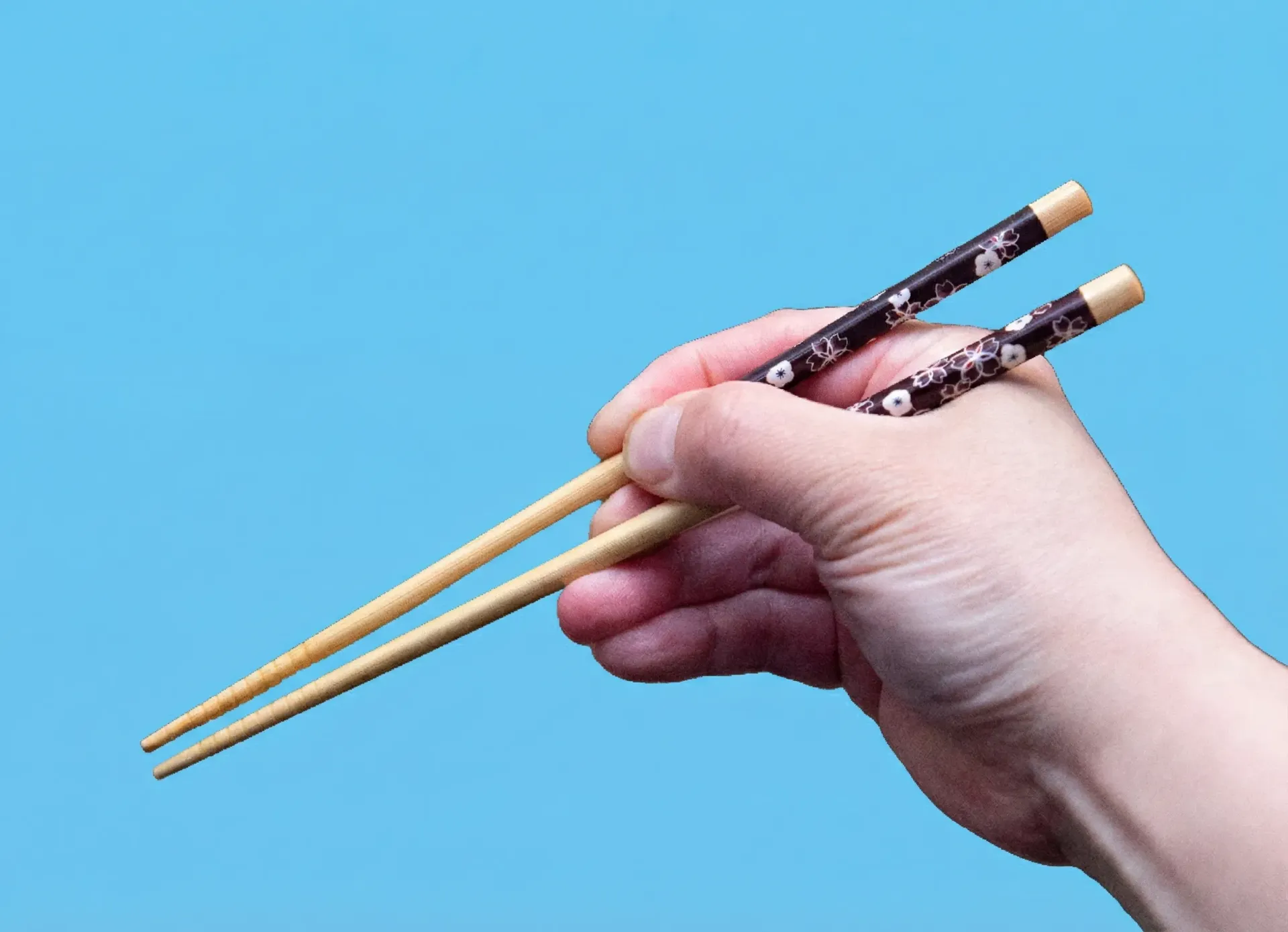 Noodles with vegetables in a white oval bowl on a wood table, chopsticks resting on the noodles.