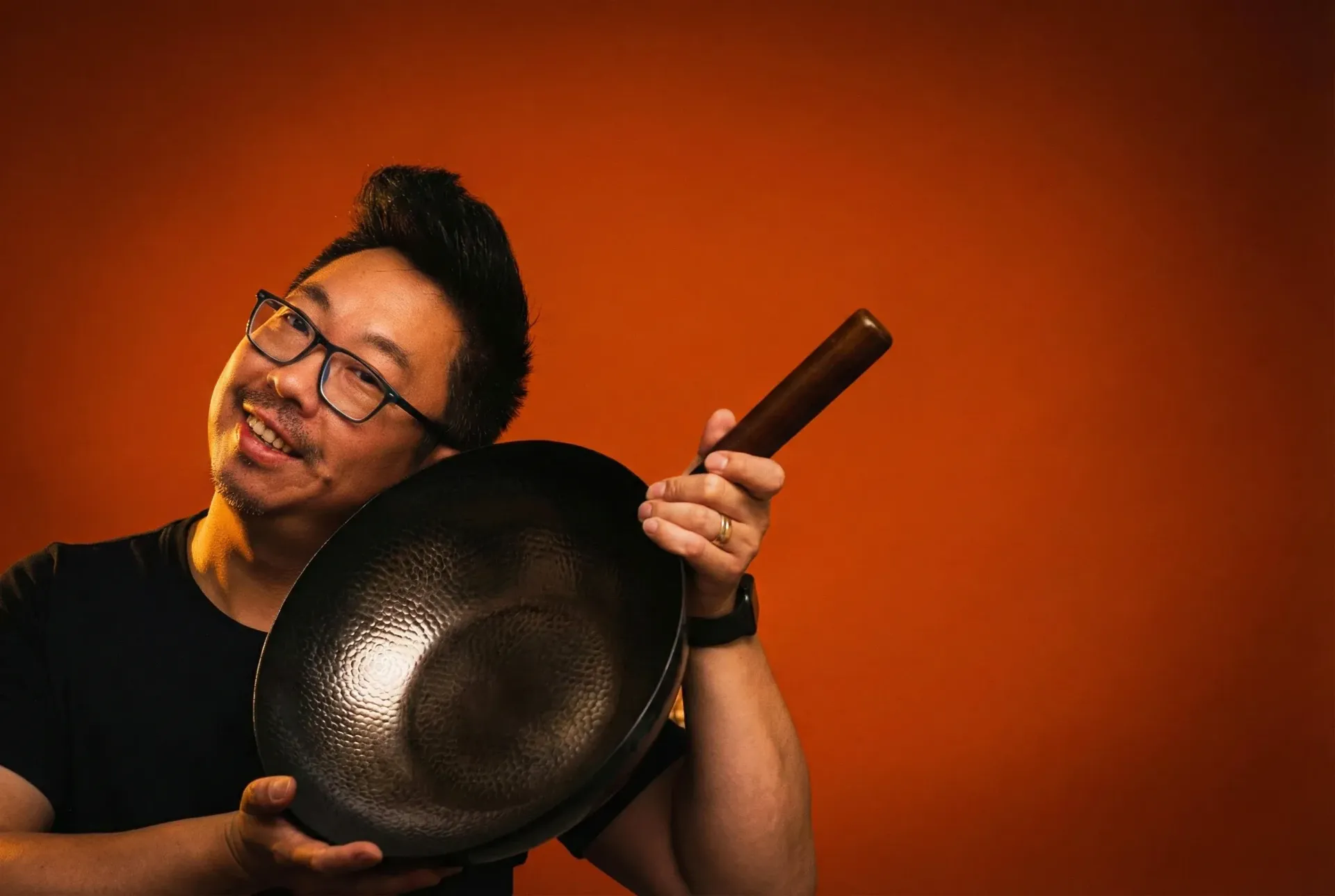 Boy holding sushi roll with chopsticks, looking surprised, indoors.