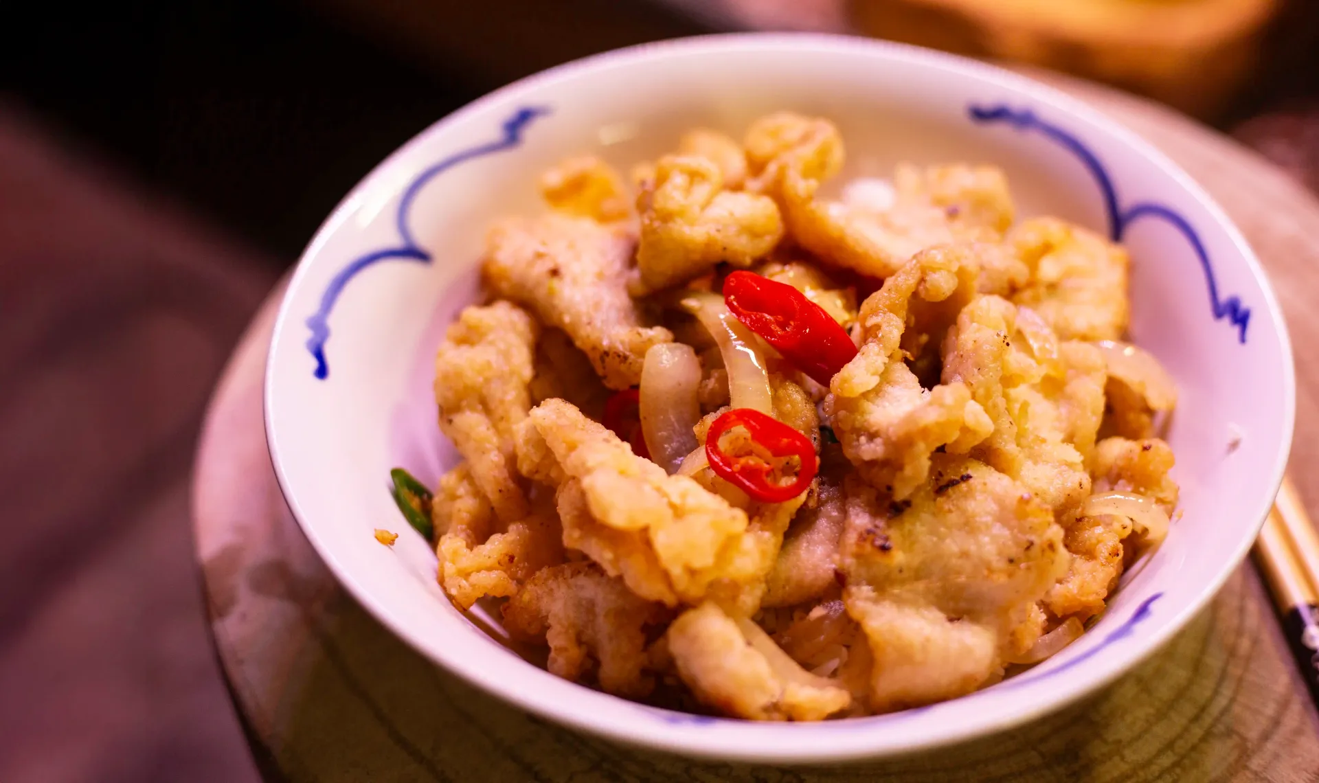 Takeout box of fried food with sauce and a sweet dough ball.