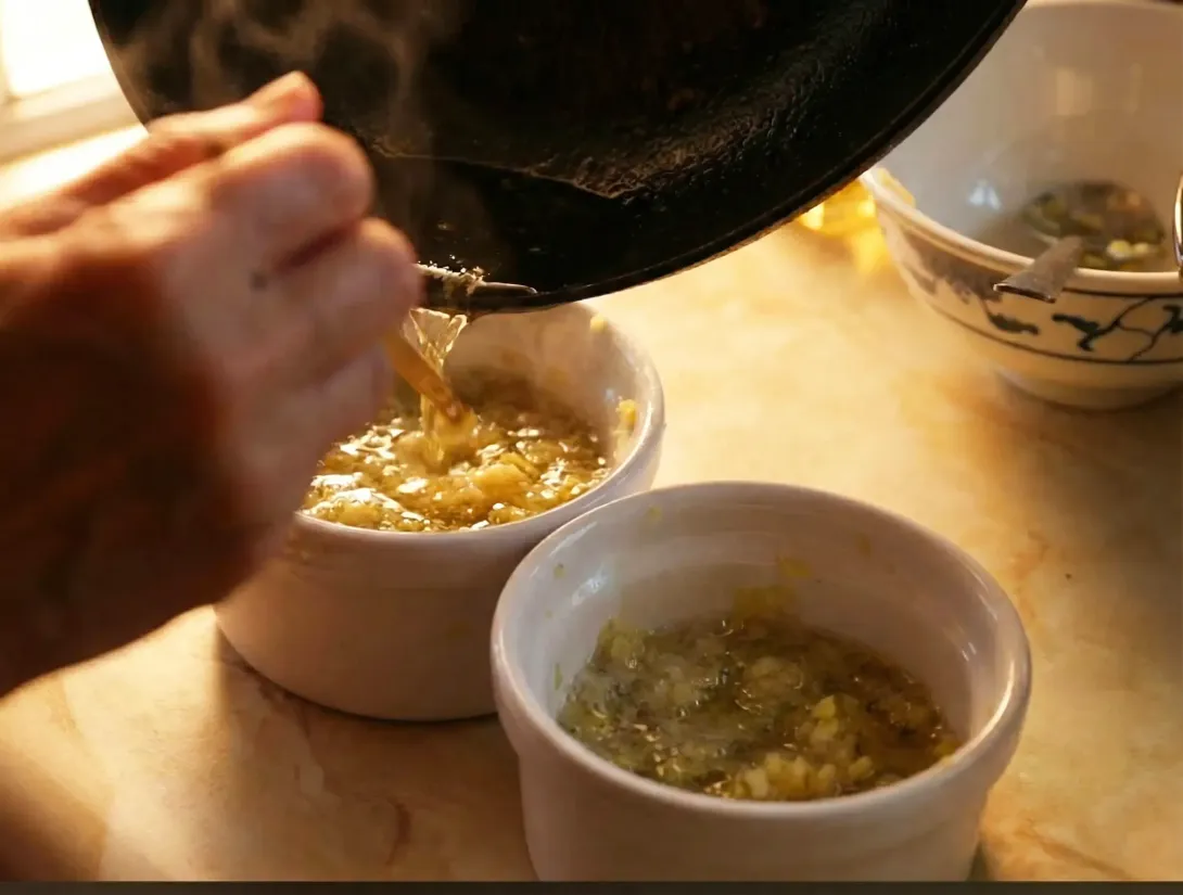 Wok cooking over high flames; a chef stirs noodles and ingredients in a black wok.