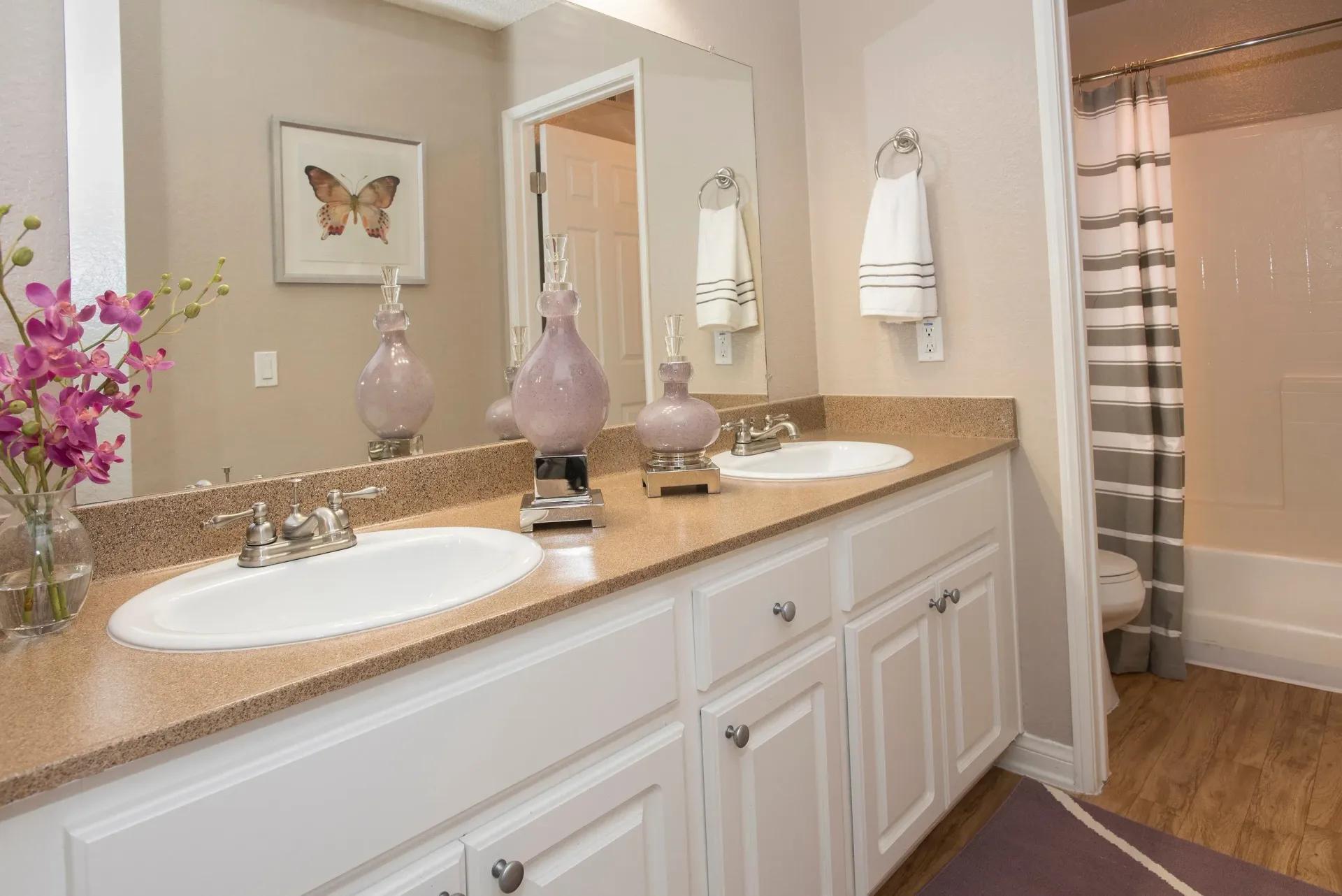 Double-sink bathroom vanity with a large mirror and a shower-tub.