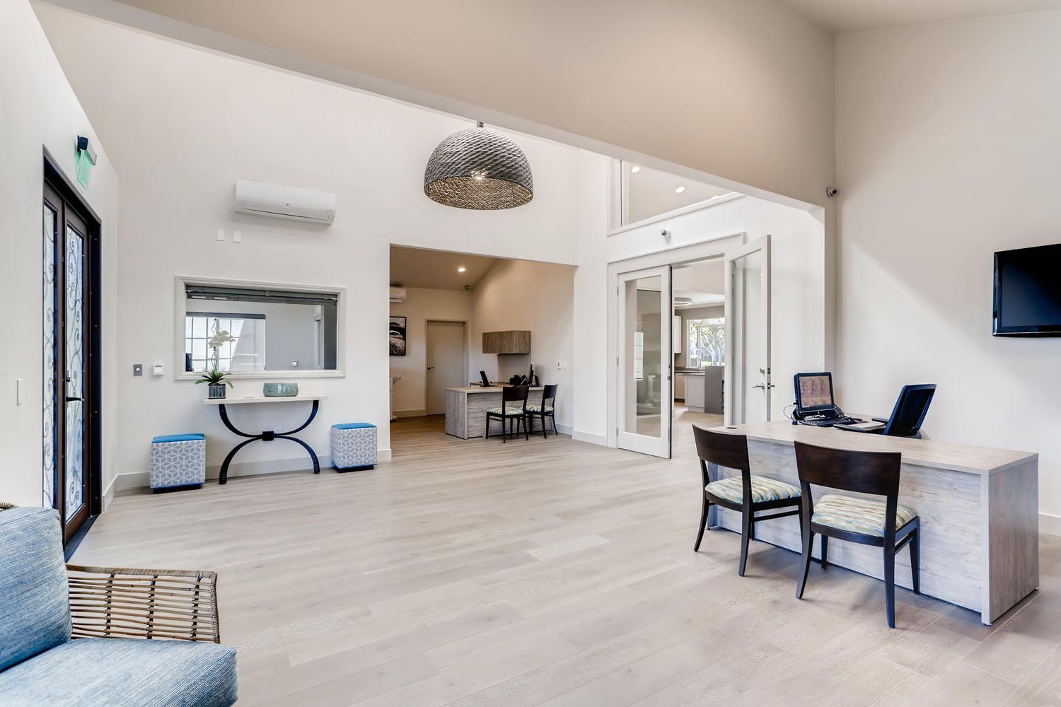 Bright, modern community lounge with a desk, seating area, and glass doors.