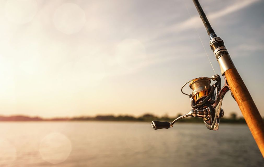 A close up of a fishing rod and reel on a lake.