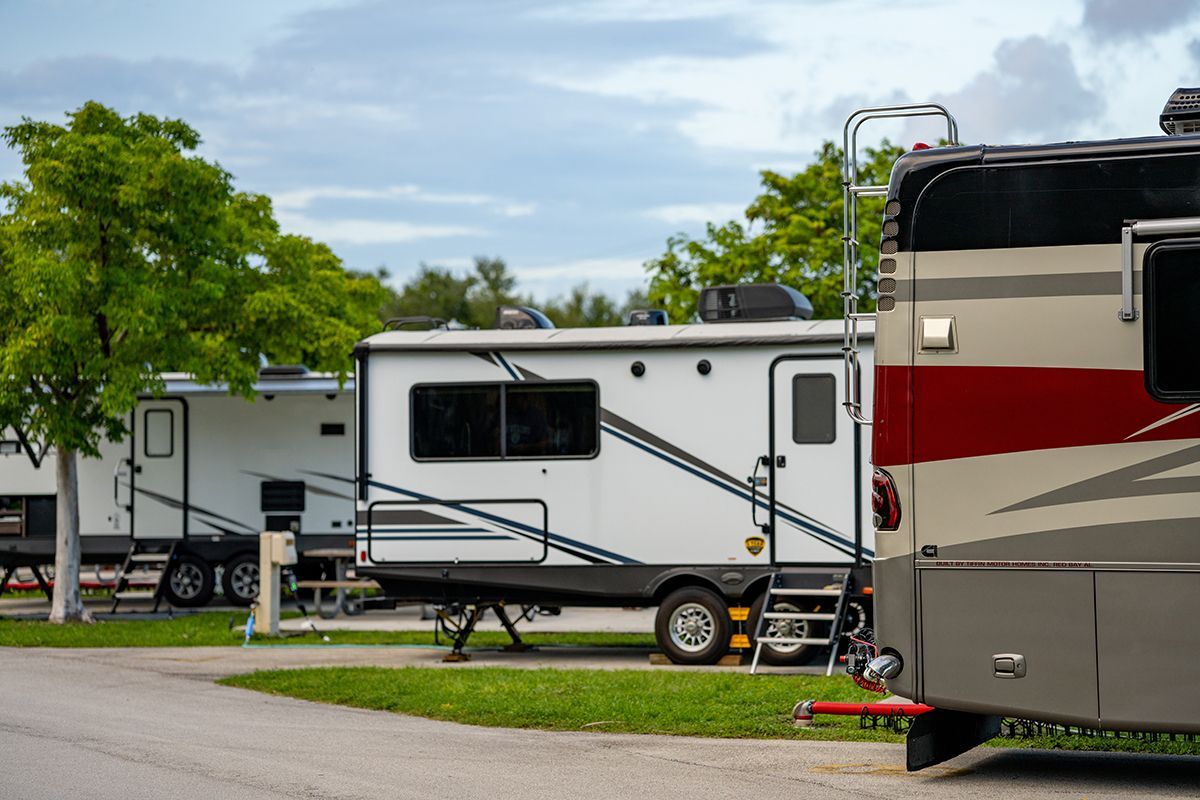 A row of rvs are parked in a campground.