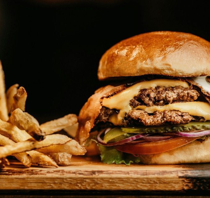 A hamburger and french fries are on a wooden cutting board.