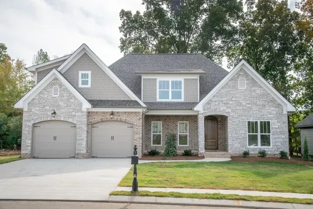 A large brick house with two garages and a driveway