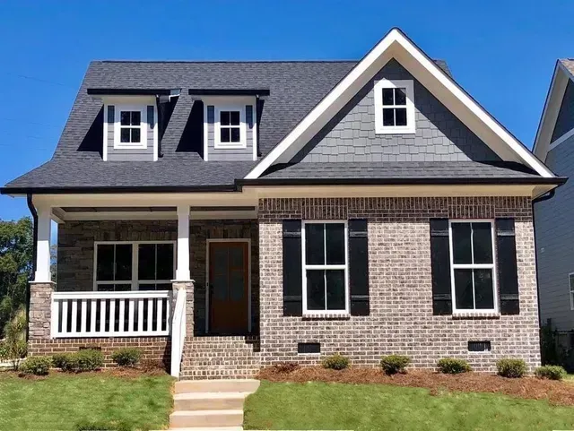 A brick house with a gray roof and black shutters