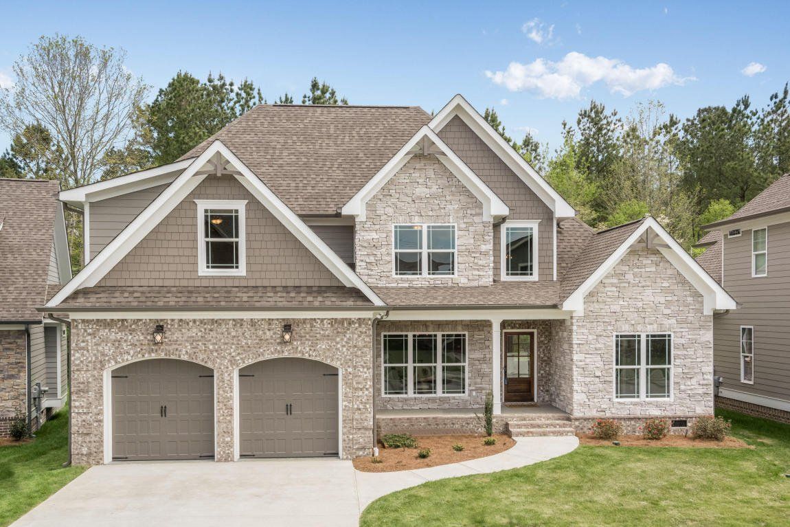 A large brick house with two garages and a large driveway.