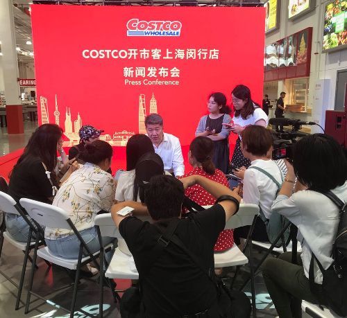 A group of people sitting in front of a costco sign