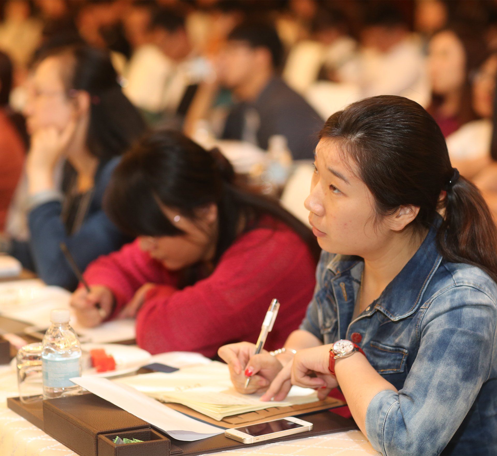 A woman sits at a table with a pen in her hand