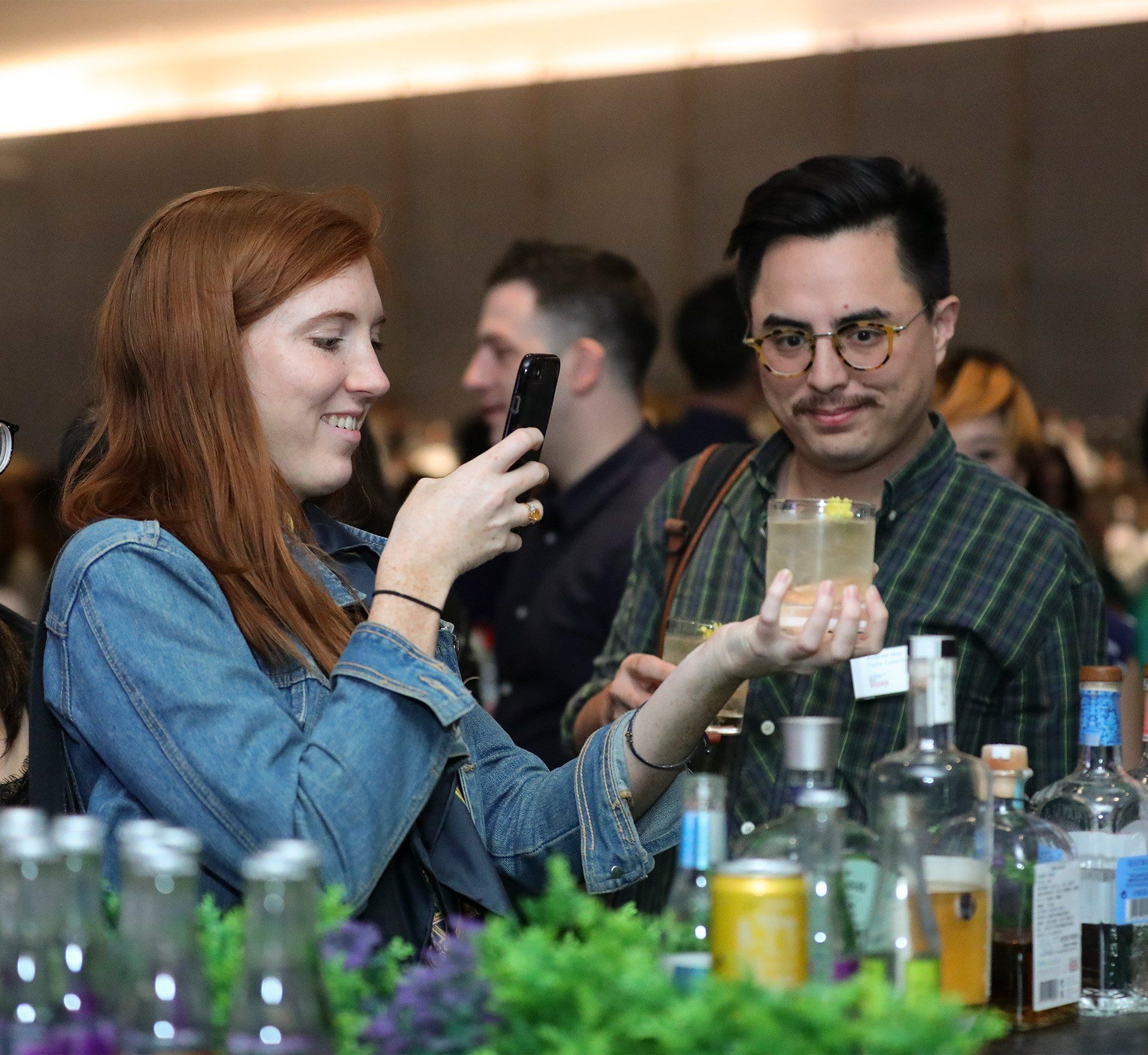 A woman is taking a picture of a man holding a drink