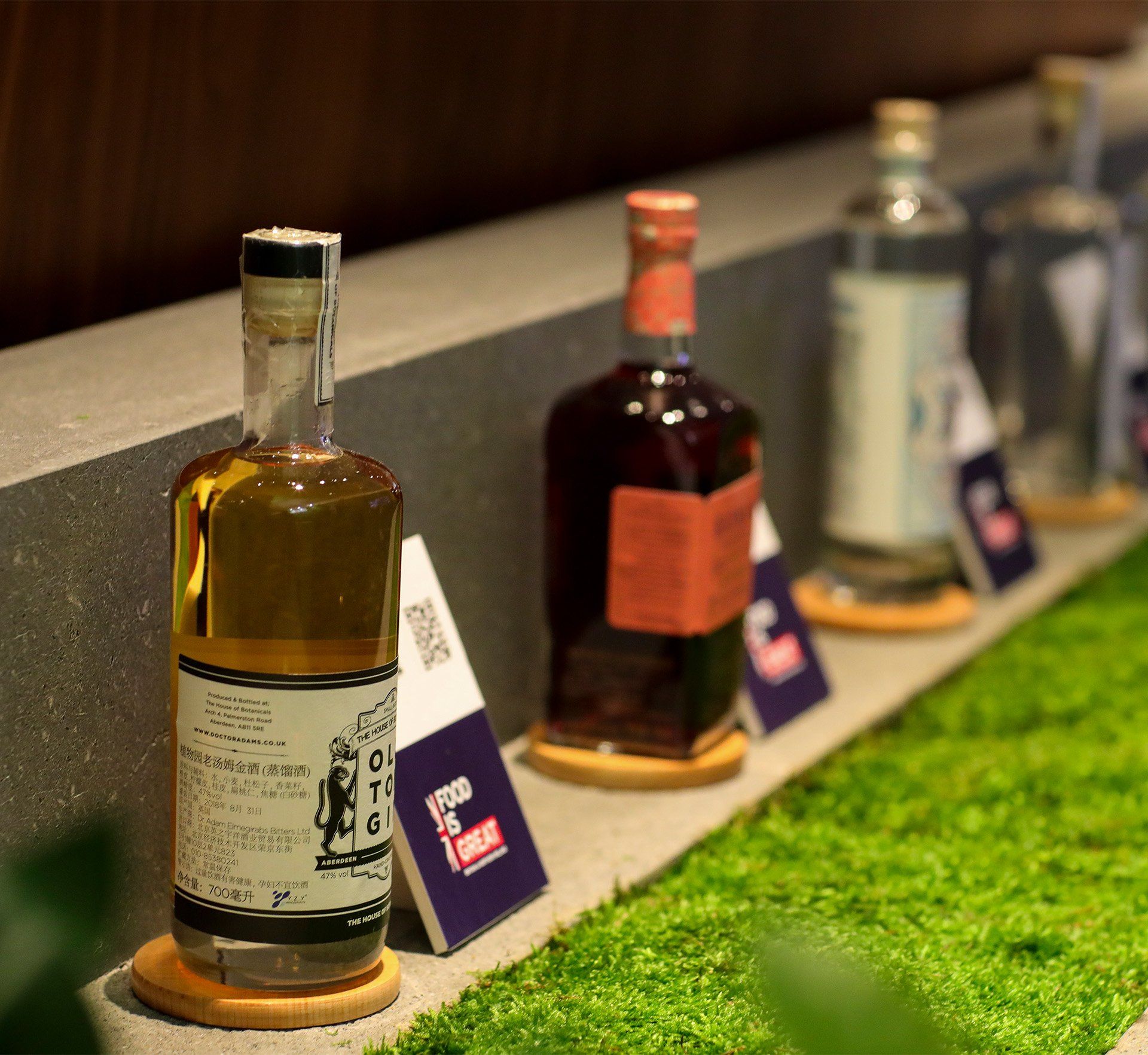 Several bottles of alcohol are lined up on a shelf