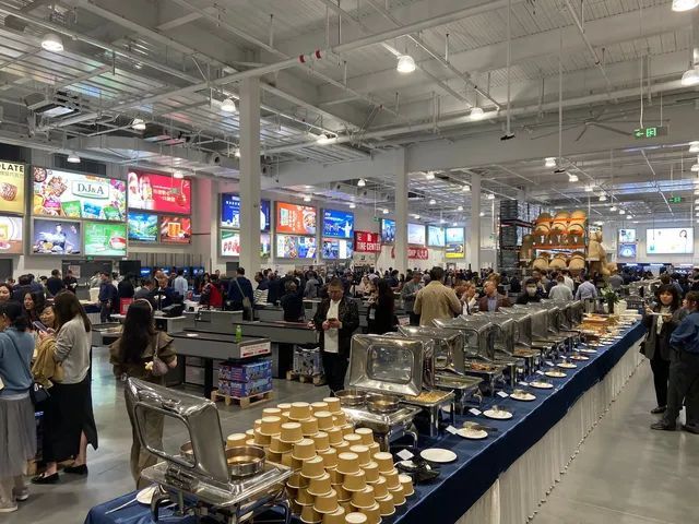 A large room filled with people standing around tables and buffets.