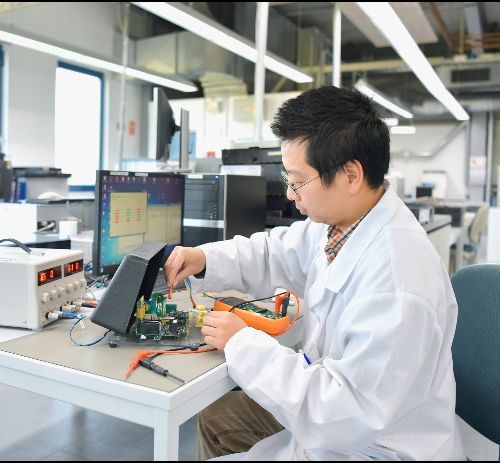 A man in a lab coat is working on an electronic device