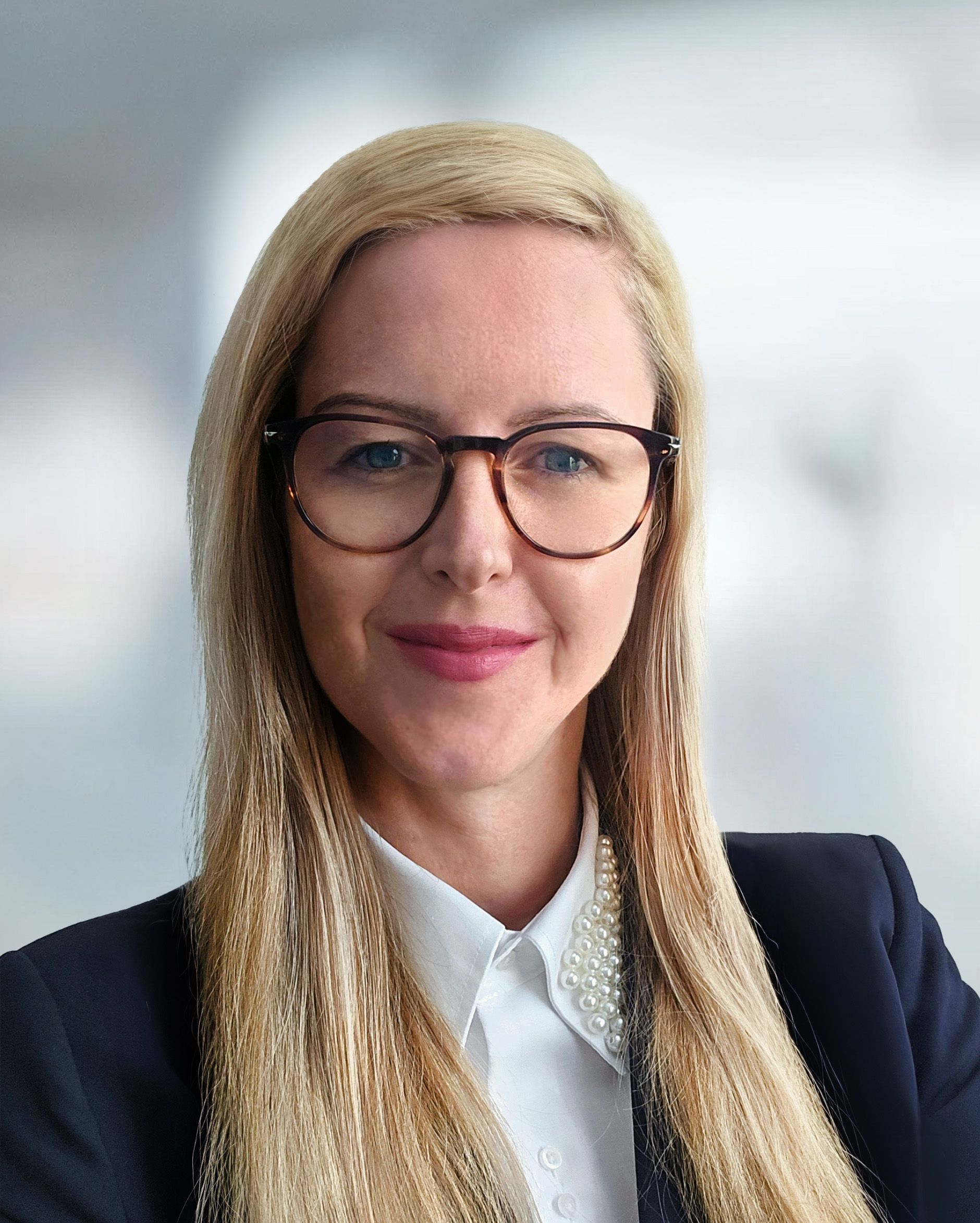 A woman wearing glasses and a suit is smiling for the camera.